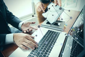 business documents on office table with smart phone and digital tablet and stylus and two colleagues discussing data in the background-1